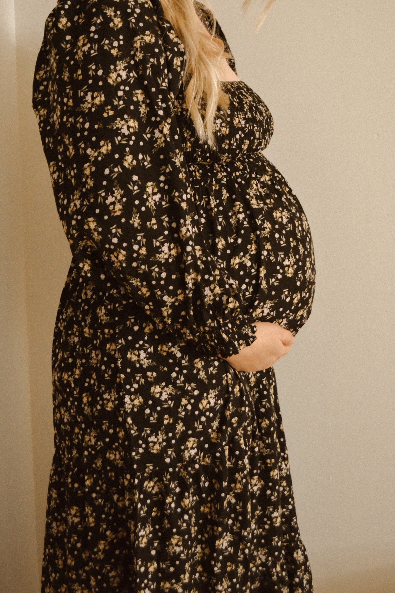 woman wearing a black floral maternity dress with a baby bump visible