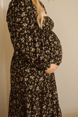 woman wearing a black floral maternity dress with a baby bump visible