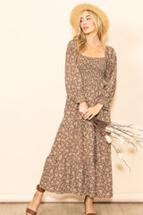 woman wearing a brown floral maxi dress with long sleeves and a smocked bodice, holding dried flowers and wearing a straw hat