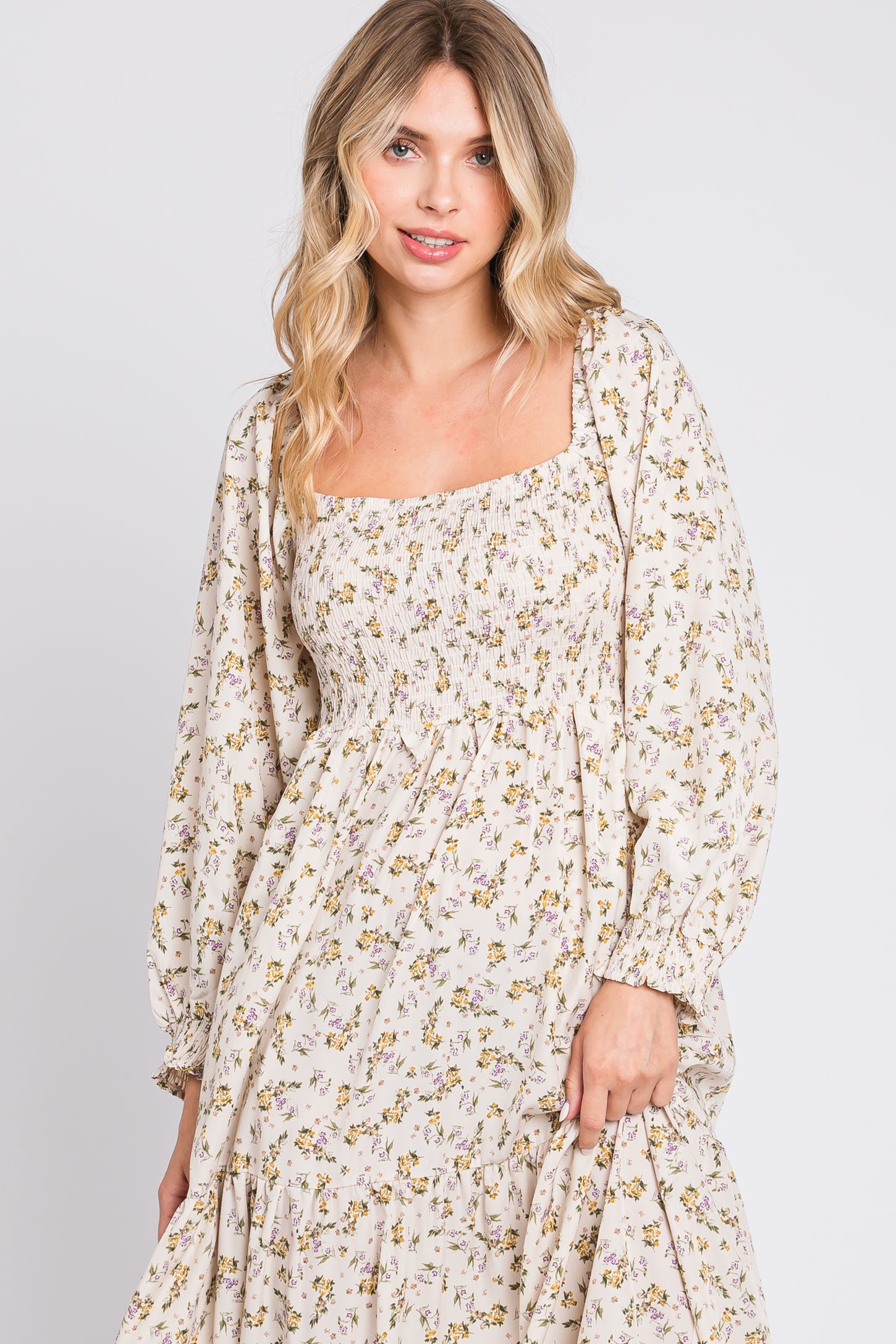woman wearing a cream floral maxi dress with a square neckline and long puff sleeves