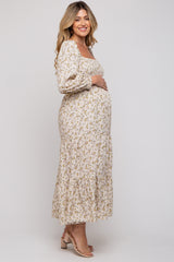 woman wearing a floral long sleeve maternity dress with a tiered skirt and holding her baby bump