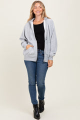 woman wearing a grey oversized hoodie paired with a black tank top and blue skinny jeans