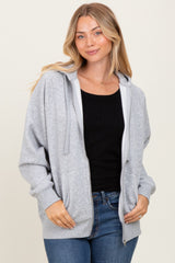 woman wearing a gray zip-up hoodie over a black sweater and blue jeans