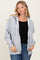 woman wearing a gray zip-up hoodie over a black sweater and blue jeans