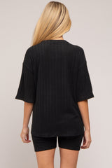 woman wearing a black ribbed maternity top and matching shorts, showing the back view and a baby bump.