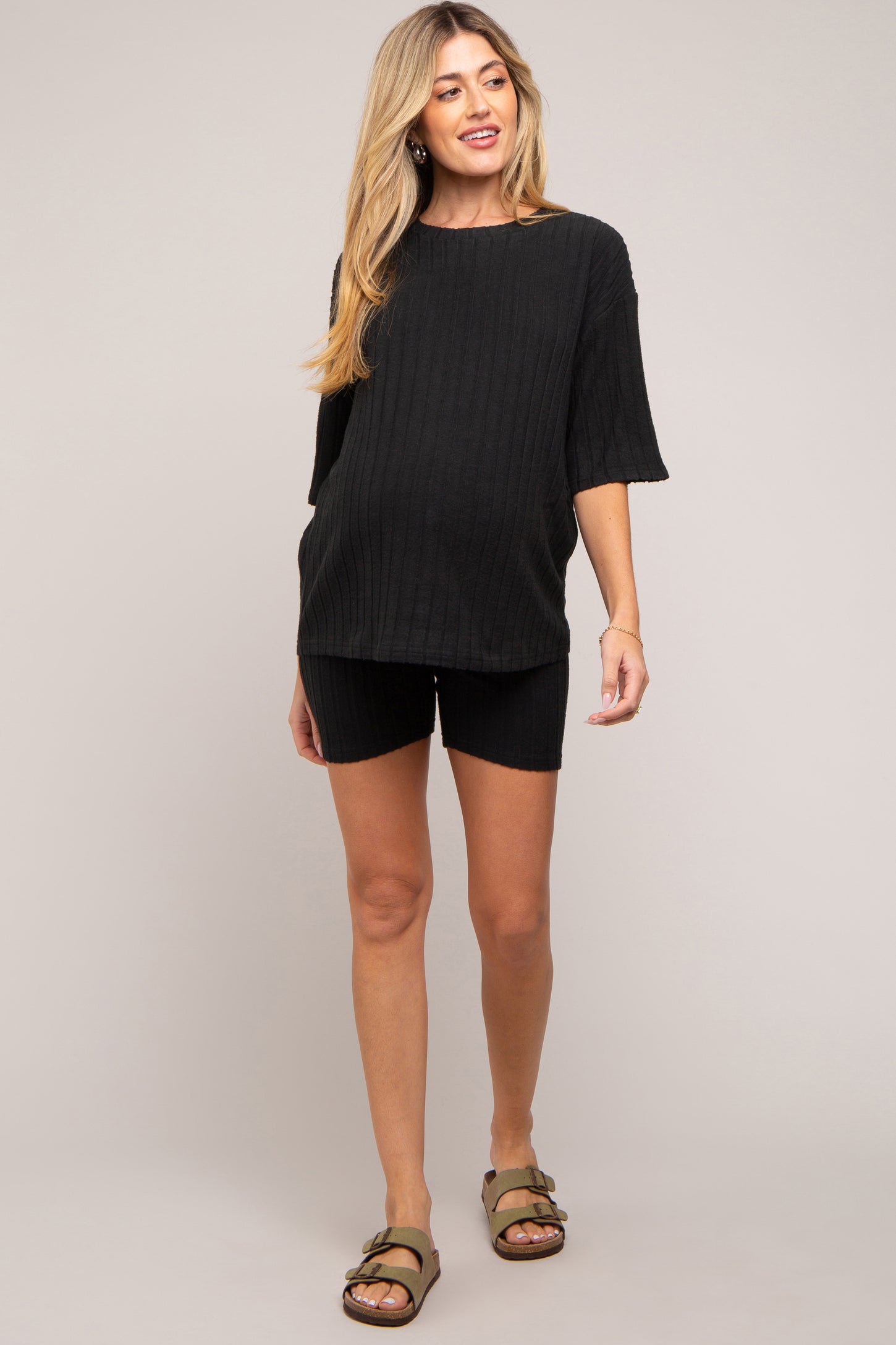 woman wearing a black maternity knit oversized top and matching shorts, showing her baby bump