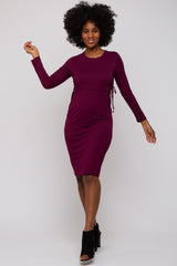woman wearing a burgundy long sleeve fitted dress with side tie details and black ankle boots