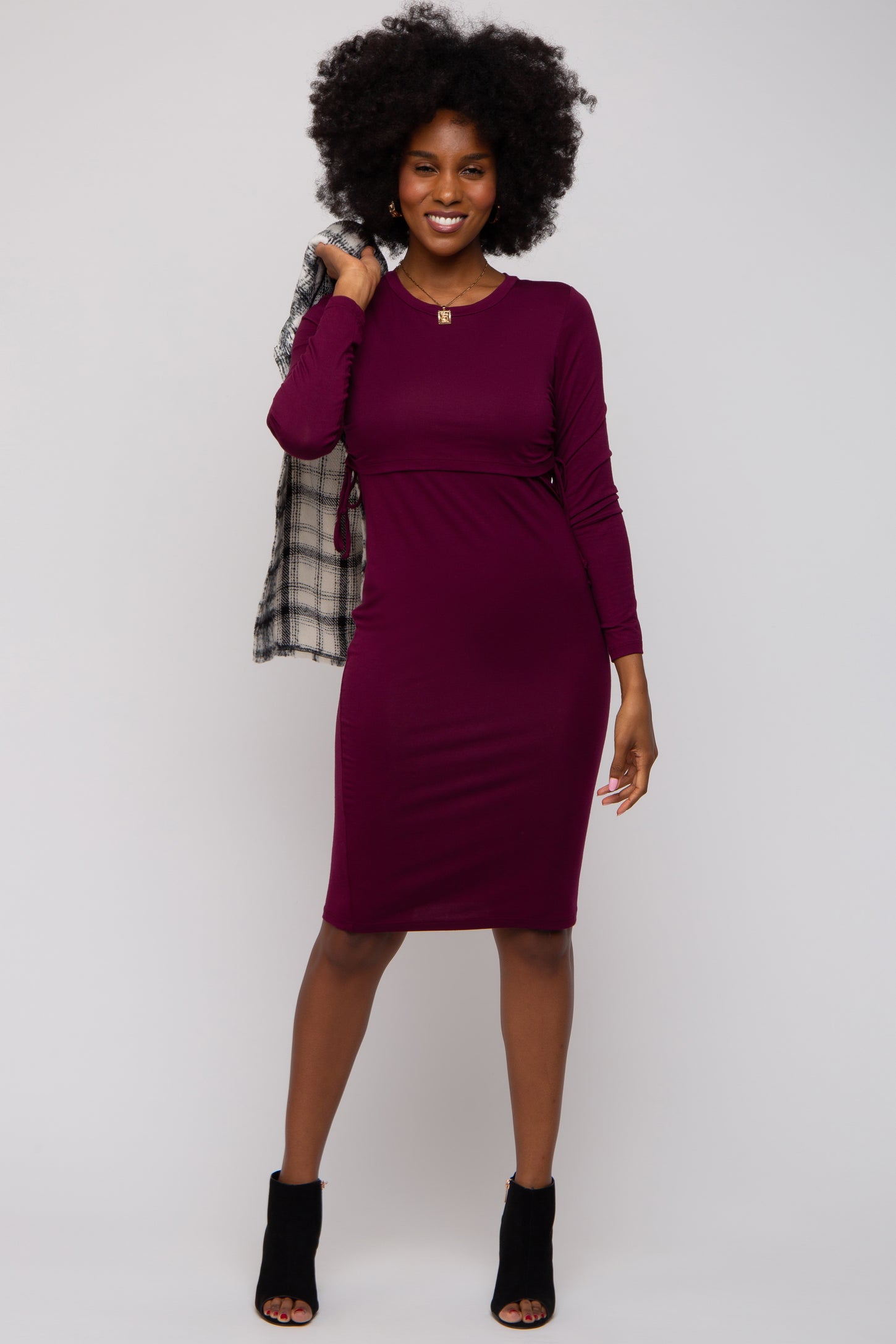 woman wearing a burgundy long sleeve bodycon dress and holding a black and white checkered scarf
