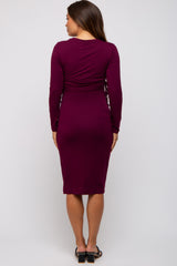woman wearing a maroon long sleeve maternity dress with ruching details in a fitted style