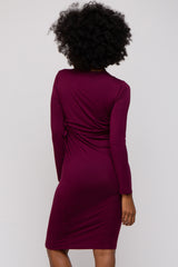 woman wearing a burgundy long sleeve fitted dress with side tie detail