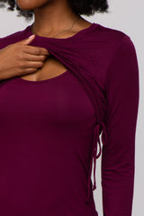 woman wearing a burgundy long sleeve top with side ruching for adjustable fit