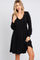 woman wearing a black long sleeve dress with a scooped neckline and a flowy skirt