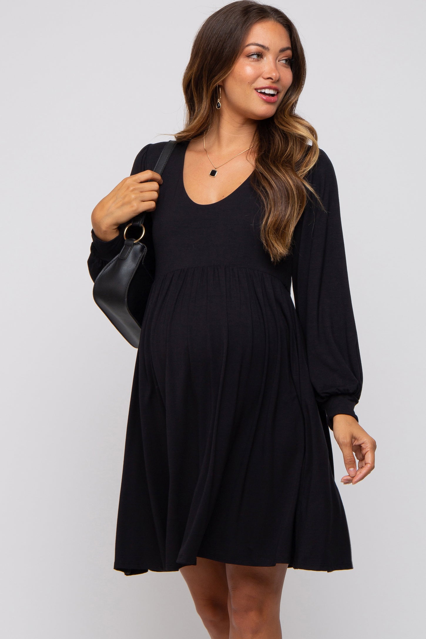 woman wearing a black long sleeve maternity dress with a v-neck and baby bump visible
