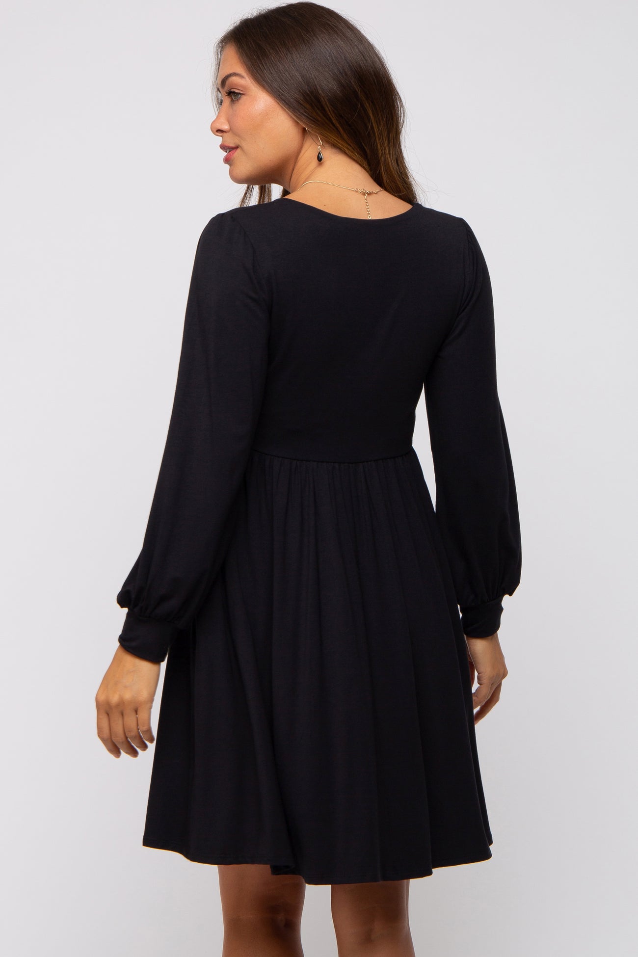 woman wearing a black long sleeve maternity dress with a fitted bodice and flared skirt