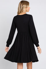 woman wearing a black long sleeve dress with a fitted bodice and flared skirt, viewed from the back