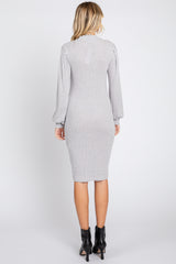 woman wearing a grey ribbed midi dress with puff sleeves and a back slit, styled with ankle booties