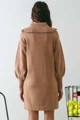 woman wearing a camel-colored sweater dress with a large collar and puffed sleeves, viewed from the back