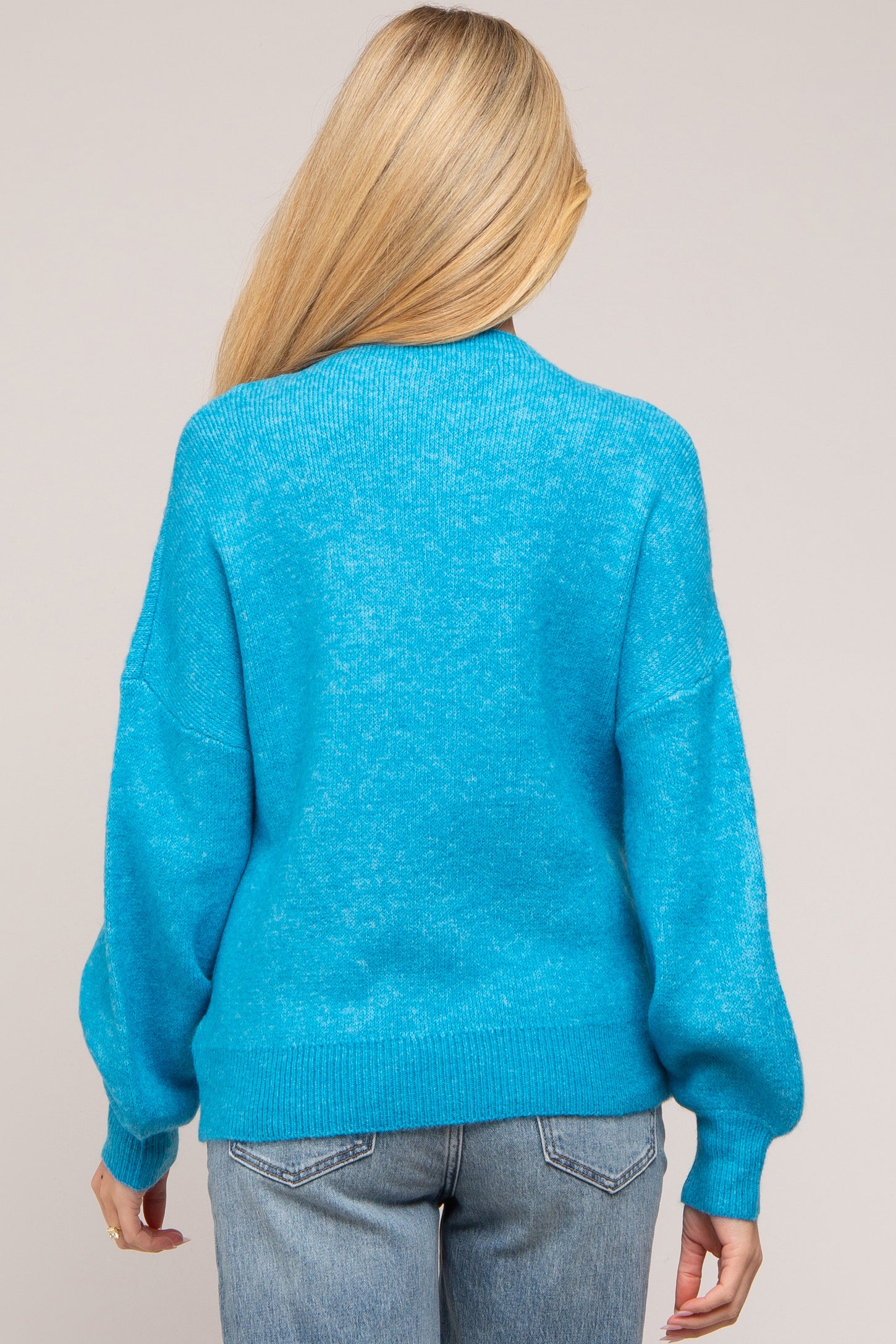 woman wearing a bright blue oversized maternity sweater with balloon sleeves, viewed from the back
