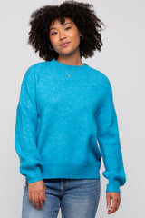 woman wearing a bright blue oversized sweater with long sleeves and a relaxed fit, paired with denim jeans