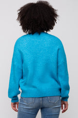 woman wearing a bright blue oversized sweater with a relaxed fit and long sleeves, viewed from the back
