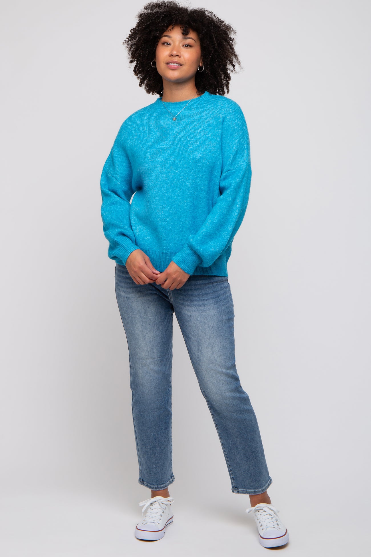 woman wearing a bright blue oversized sweater and light wash straight leg jeans with white sneakers