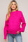 woman wearing a bright pink maternity sweater with a relaxed fit and long sleeves, showing her baby bump