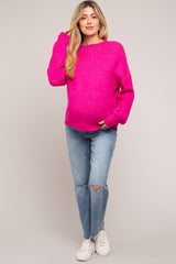 woman wearing a bright pink maternity sweater and distressed jeans, holding her baby bump