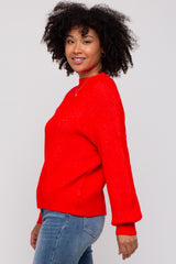 woman wearing a bright red sweater with long sleeves and a relaxed fit paired with blue jeans
