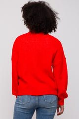 woman wearing a red oversized sweater with a high neck and relaxed fit, paired with blue jeans