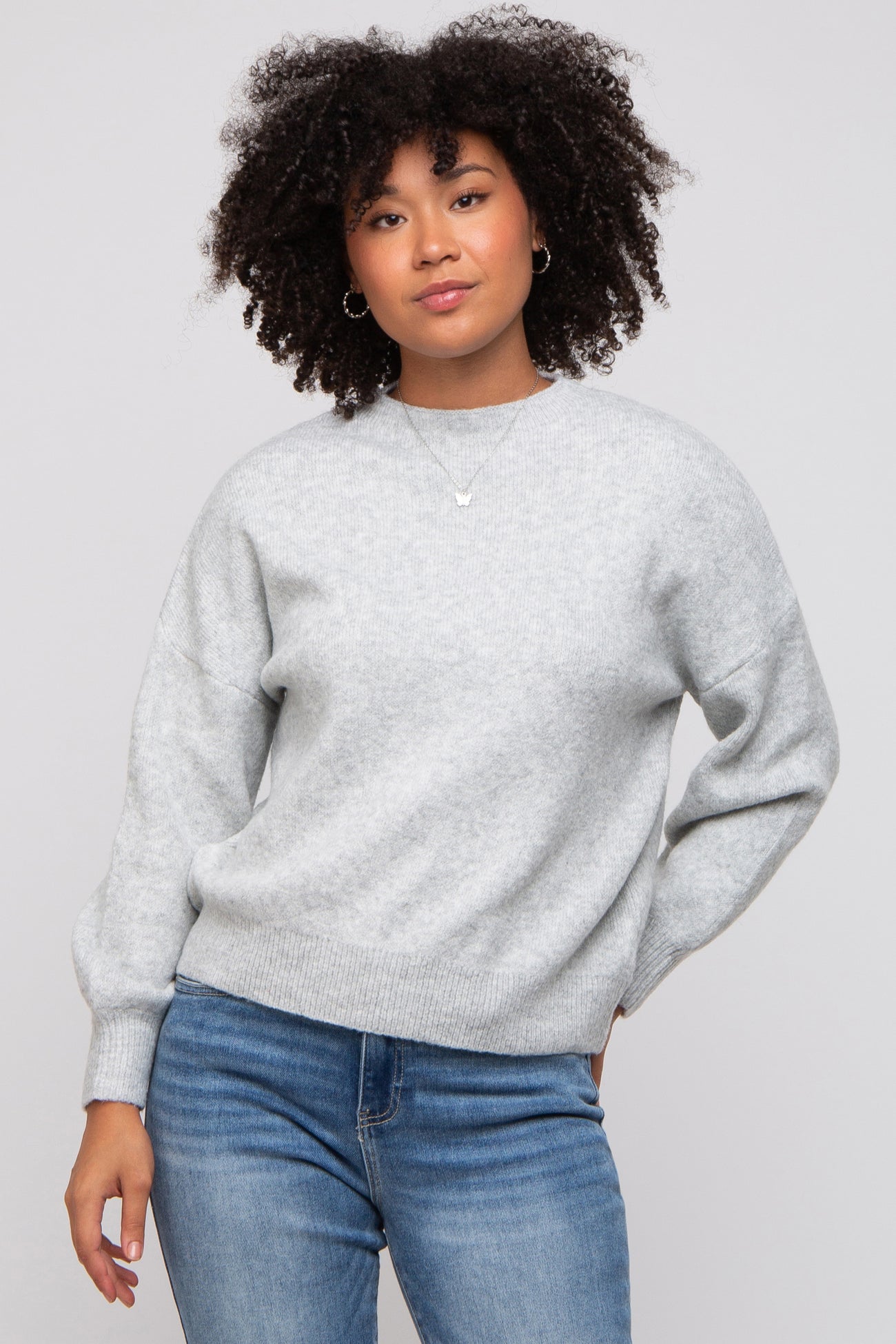 woman wearing a light gray oversized sweater with balloon sleeves paired with blue jeans