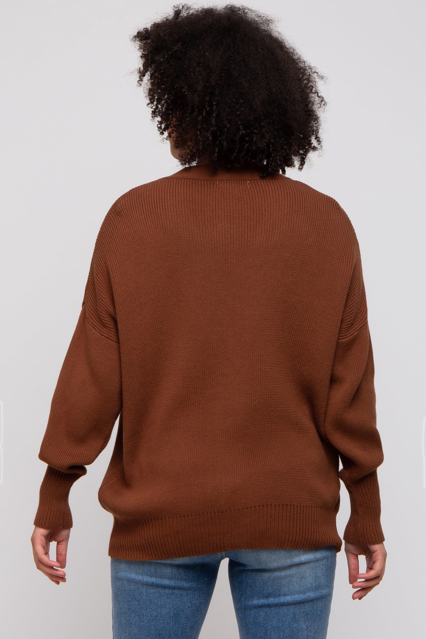 woman wearing a brown oversized sweater with a ribbed texture and a relaxed fit, viewed from the back