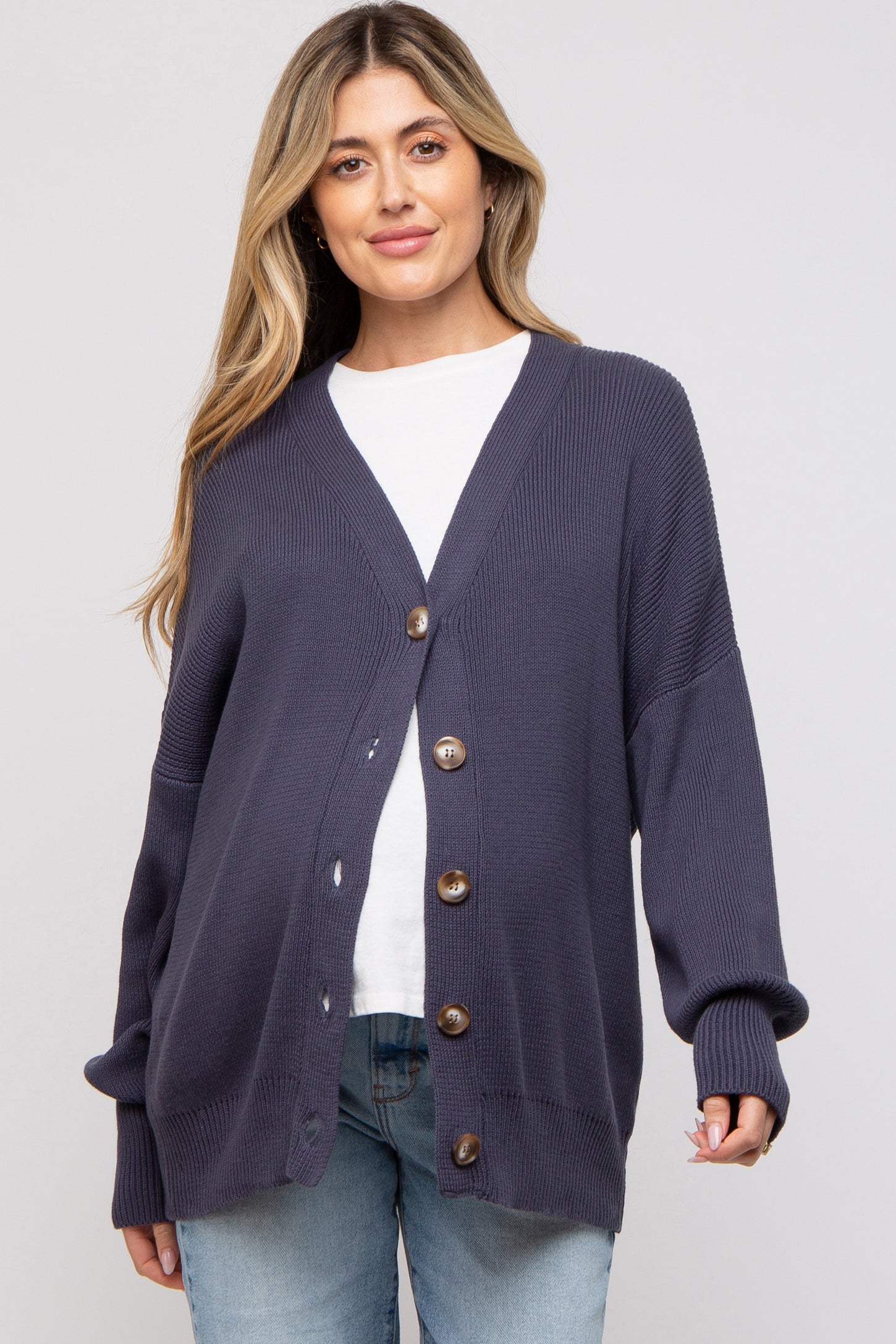 woman wearing a navy blue maternity cardigan with buttons and a v-neck, styled over a white t-shirt and jeans