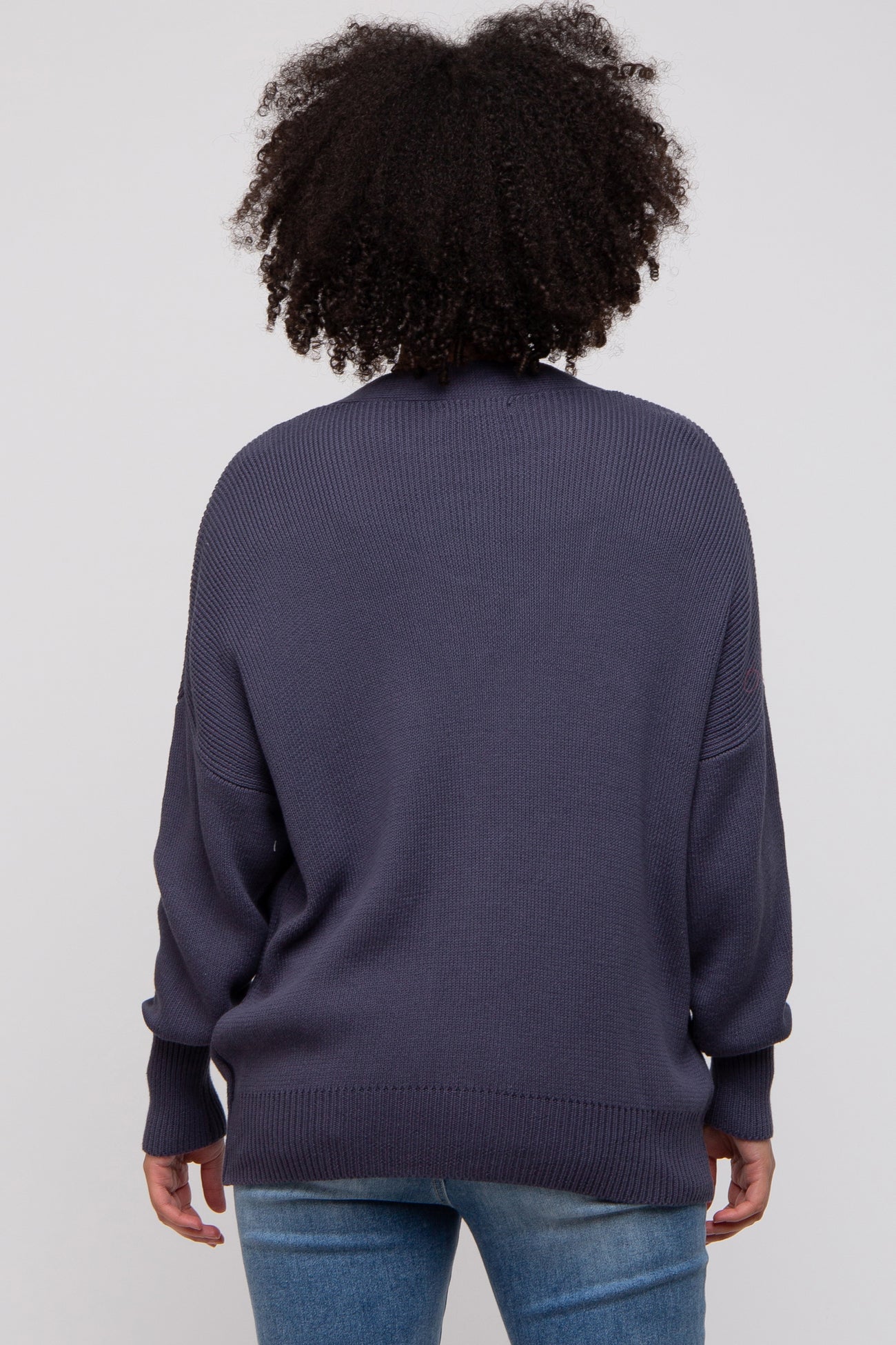 woman wearing a dark blue oversized sweater with a loose fit and long sleeves, seen from the back