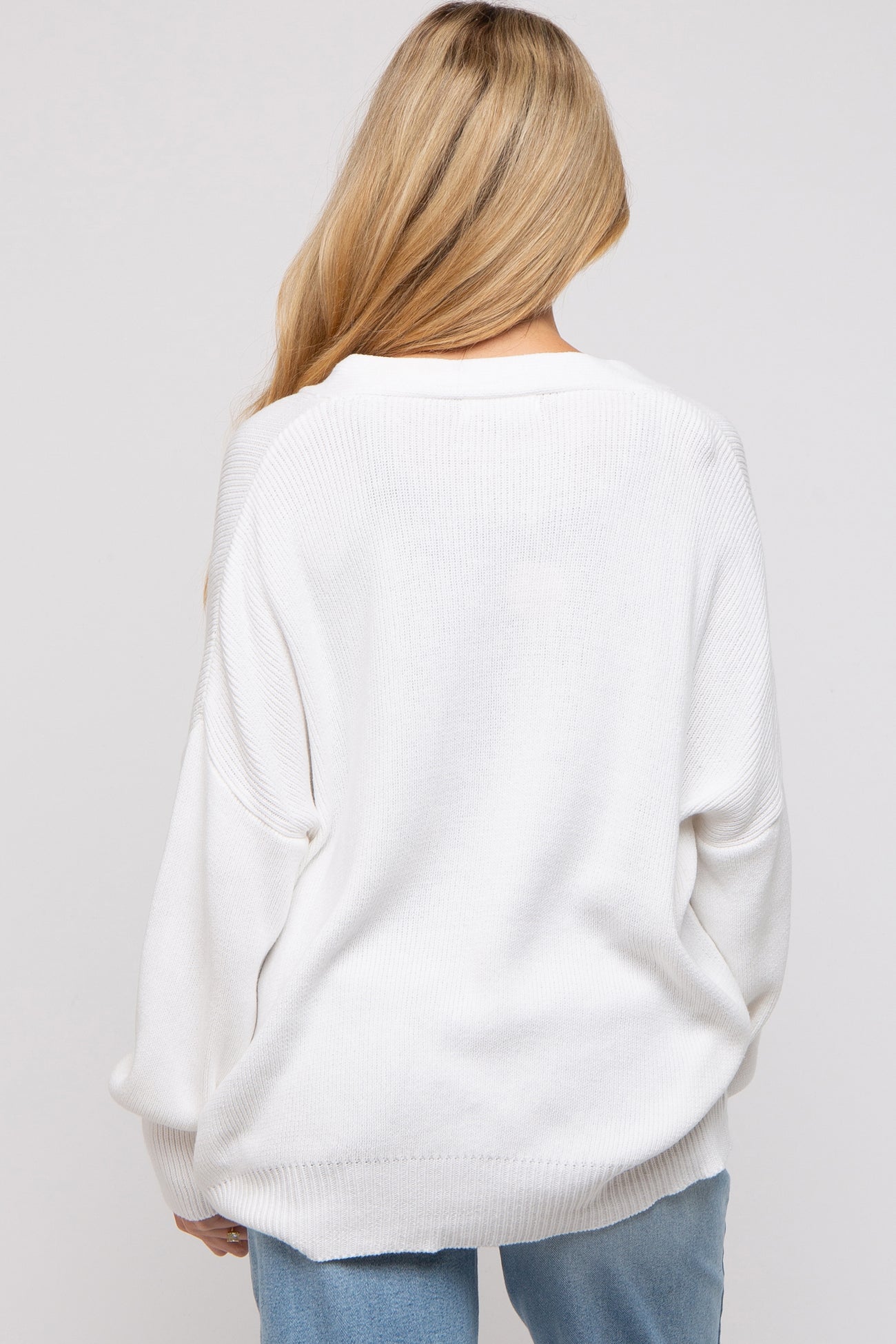 woman wearing a loose-fitting white maternity sweater with a relaxed silhouette and dropped shoulder seams