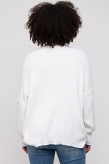woman wearing a white oversized sweater with ribbed detailing, seen from the back, paired with blue jeans
