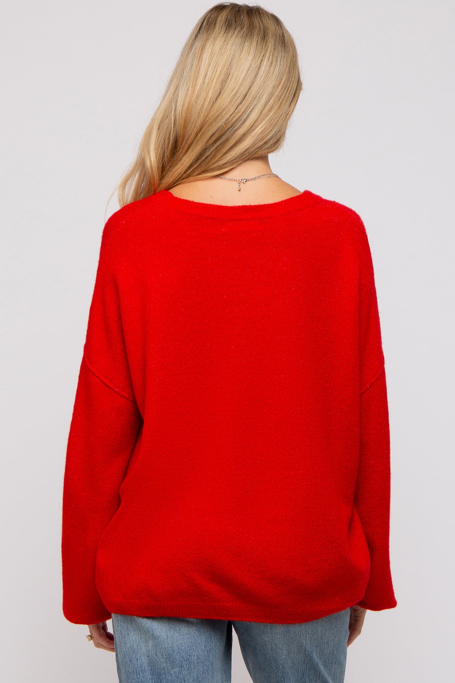 woman wearing a red oversized maternity sweater with a relaxed fit, viewed from the back
