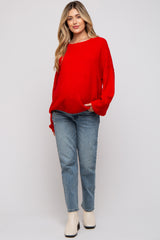 woman wearing a red oversized sweater and light blue straight leg jeans, styled casually in maternity wear
