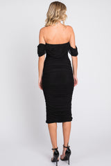 woman wearing a black off-shoulder bodycon dress with ruched detailing, showing the back view
