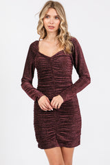 woman wearing a burgundy long sleeve ruched bodycon dress with a sweetheart neckline