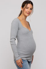 woman wearing a gray ribbed long sleeve maternity top and showing her baby bump