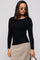 woman wearing a black long sleeve top paired with a beige skirt and stylish sunglasses