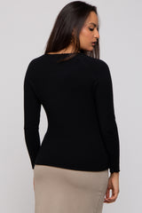 woman wearing a fitted black long sleeve sweater, showing a close back view of the garment