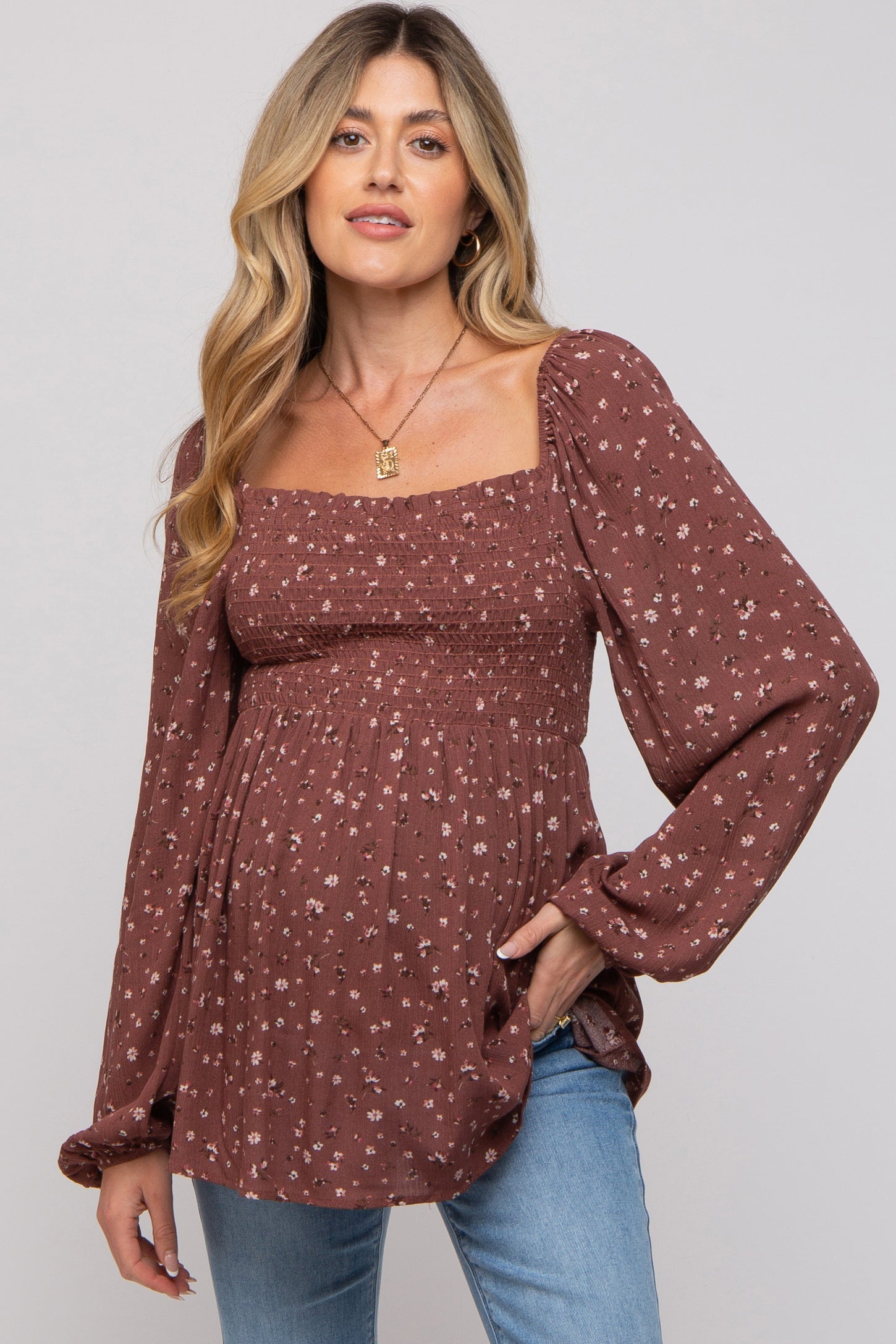 woman wearing a brown floral maternity top with a smocked bodice and puff sleeves, showing her baby bump