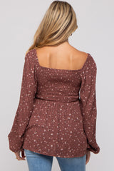 woman wearing a brown floral maternity top with smocked bodice and long sleeves, showing the back view