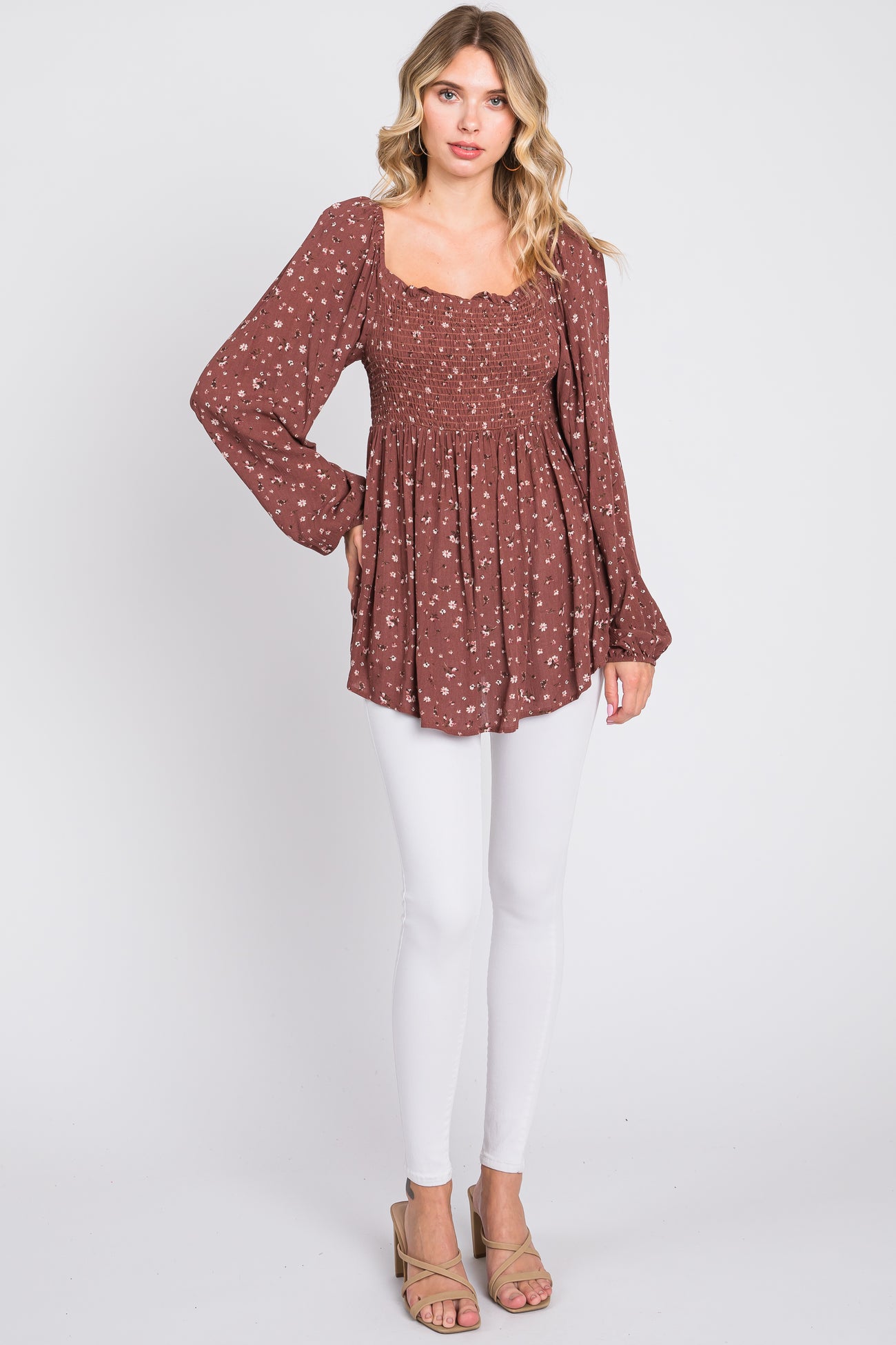 woman wearing a brown floral smocked blouse with long sleeves and white skinny jeans