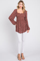 woman wearing a brown floral smocked blouse with long sleeves and white skinny jeans