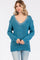 woman wearing a teal oversized sweater with lace trim around the v-neckline and relaxed fit paired with light jeans