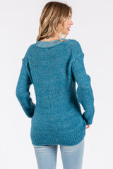 woman wearing a teal oversized sweater with lace detail at the neckline and styled with light blue jeans