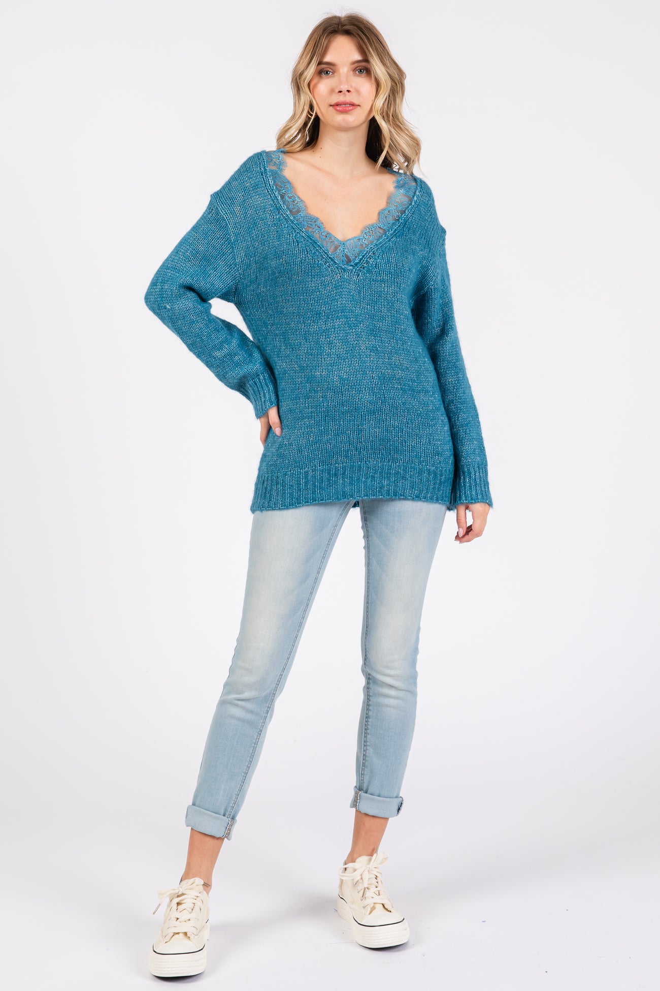 woman wearing a teal oversized v-neck sweater paired with light blue skinny jeans and white sneakers