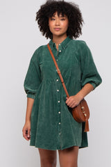 woman wearing a green denim shirt dress with puff sleeves and button detailing, holding a brown crossbody bag